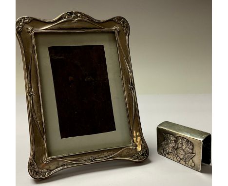 A George V silver easel arched photograph frame, embossed with leafy trails, 18cm, Chester 1921; an Edwardian silver matchbox