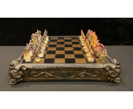 A novelty chess set, the resin pieces as myth and magic figures, the chess board with a pair of storage drawers, 50cm wide 
