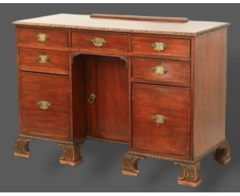 A 19th Century mahogany kneehole desk, the carved moulded top above seven drawers and central cupboard with carved bracket fe