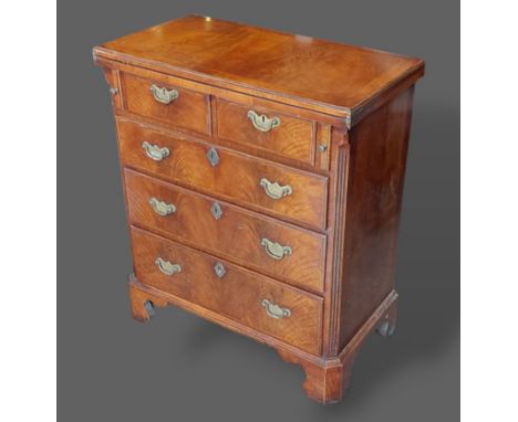A 20th Century walnut batchelors chest, the hinged top with herringbone inlay above two short and three long drawers with bra