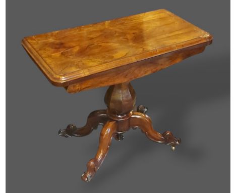 A William IV Rosewood card table, the hinged top above an octagonal baluster column raised upon four carved legs with scroll 