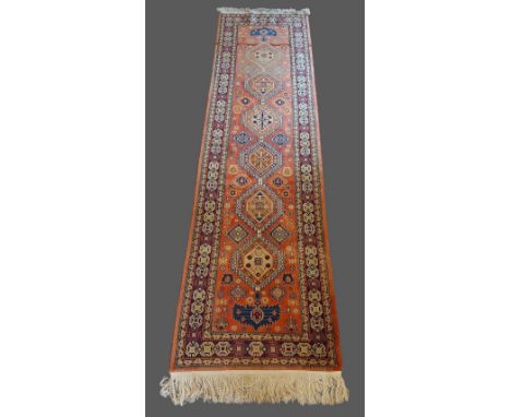 A North west Persian woollen runner with an all over design upon a cream and red ground, 80cms by 305cms
