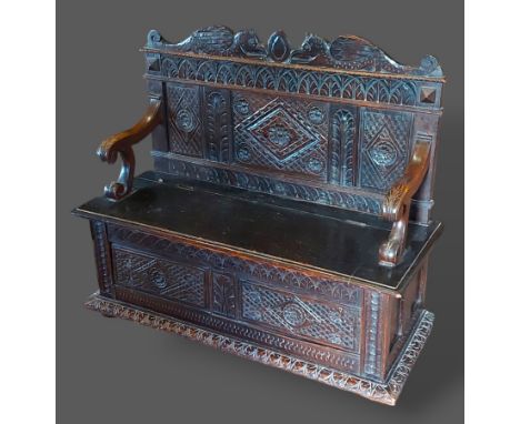 A Victorian carved oak Monks bench with a shaped carved back above a panel seat and double carved panel front, 120cms wide, 4