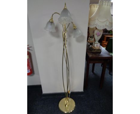 A brass three way floor lamp with glass shades 