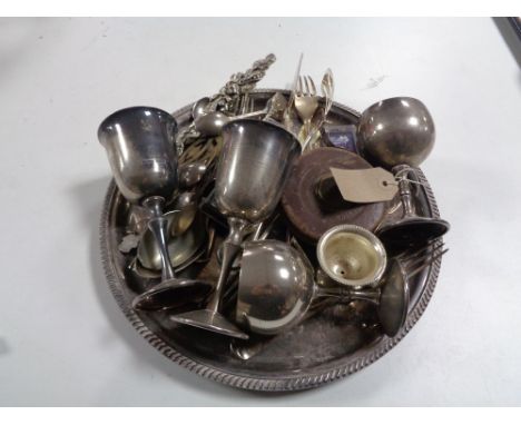 A circular plated tray containing servers and cutlery, plated goblets, vintage leather cased tape measure 
