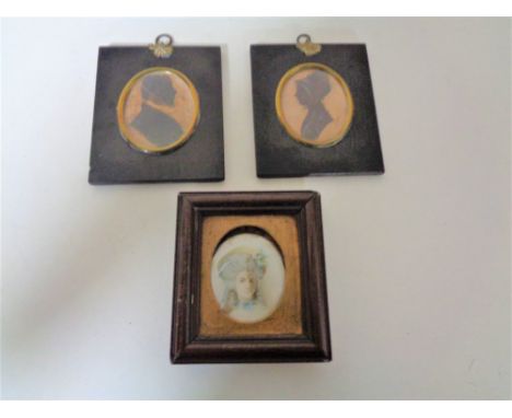Two George III silhouette type miniatures together with a further portrait miniature behind glass.