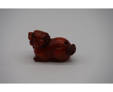 An unusual Japanese carved amber lion dog netsuke,&nbsp;4.5cm long. 