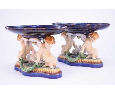 A pair of Minton majolica comports or tazzas, date code for 1864, impressed model number 930, modelled as cherubs supporting 