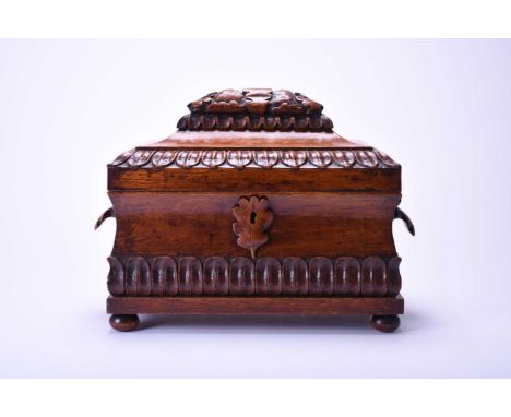 A Victorian oak tea caddyOf sarcophagus form with oakleaf cluster carrying handles, the cover and caddy carved with further o