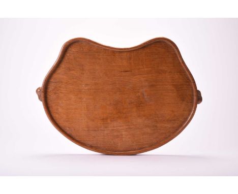 Studio of Robert Mouseman Thompson (Kilburn), an adzed oak tea trayOf kidney shape with signature mouse 'handles'.46cm wide