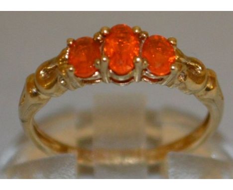 A THREE STONE ORANGE STONE RING set in 9ct gold.