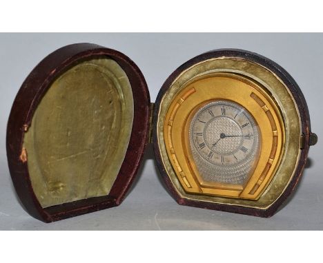 A RARE SMALL STRUTT HORSESHOE SHAPED EASEL CLOCK with engine turned silvered dial, 3ins high, in a leather carrying case.