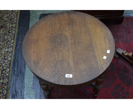 An oak occasional table, circular top, deep frieze, turned legs, X-frame stretchers, ceramic casters.