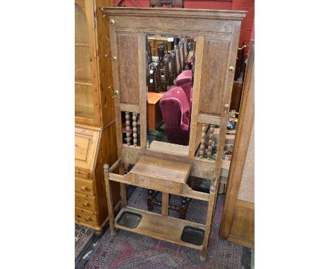 An early 20th century oak hall stand , rectangular bevel edge mirror flanked by fielded panels and bobbin turned columns, glo