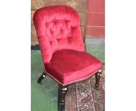 A Victorian nursing chair, button upholstered spoon back, stuffed overseat, turned and fluted forelegs, ceramic casters.C1860