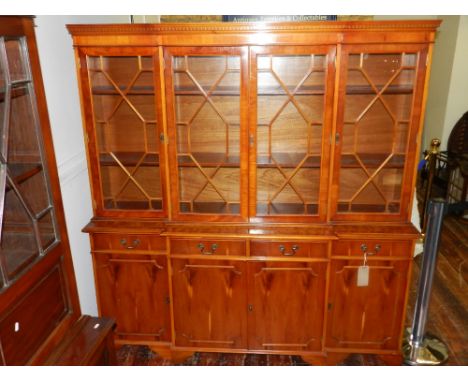 A George III style yew wood breakfront cabinet bookcase, having four astragal glazed doors above four short drawers and four 