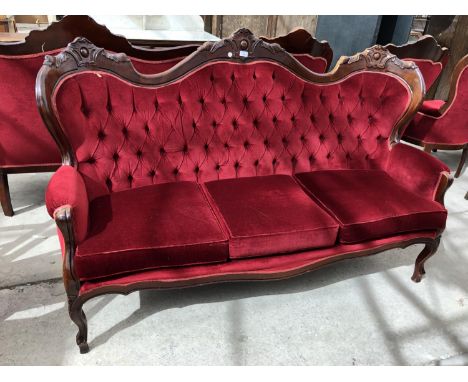 A FRENCH STYLE CARVED WOODEN AND RED BUTTON BACK UPHOLSTERED THREE SEATER SOFA 