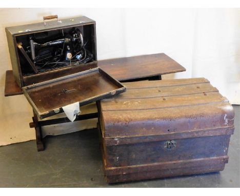 A vintage metal trunk, a trestle table and a cased singer sewing machine.