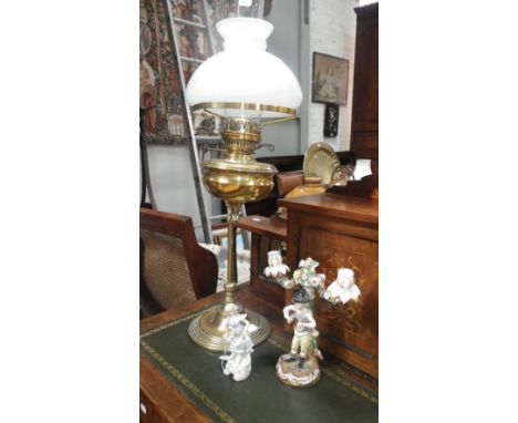 A Victorian brass adjustable student's lamp, a German porcelain Meissen style two branch candelabra and a similar figure