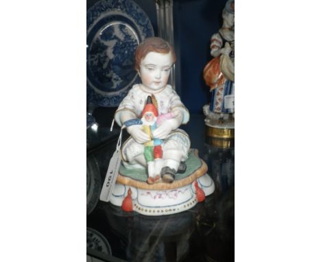 An unglazed ceramic figure of a child with a 'Punch' doll