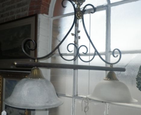 A wrought-iron style hanging kitchen light with brass fittings and opaque glass shades