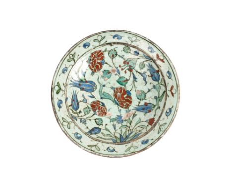 AN IZNIK POTTERY DISH WITH RED-SPECKLED BLUE TULIPS Ottoman Turkey, late 16th - early 17th centuryOf shallow rounded shape, r