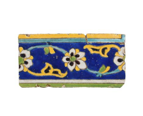 A SAFAVID CUERDA SECA POTTERY BORDER TILE Iran, 17th centuryOf narrow rectangular shape, painted in cobalt blue, yellow, gree