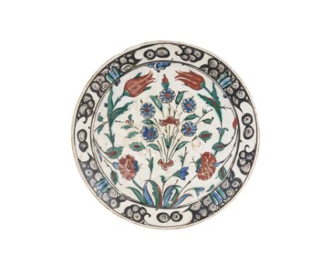 AN IZNIK POTTERY DISH WITH TULIPS, ROSES AND PLUM BLOSSOMS Ottoman Turkey, late 16th centuryOf shallow rounded shape, resting