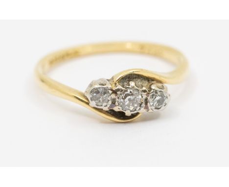 A diamond and 18ct gold three stone ring, comprising three platinum set small diamonds, cross over mount, size O, total gross