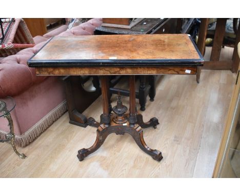 A Burr Walnut games table with four pedestal stilts to a four legged splayed base. Fabric to top when opened to show games/ca