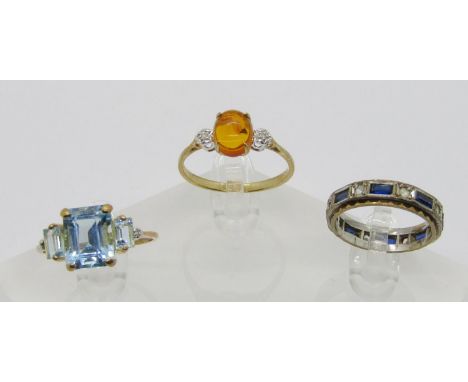 Three 9ct gem set dress rings to include a cabochon amber and diamond three stone example, a blue spinel example and an etern