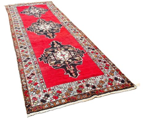 An Anatolian Turkish runner with three lozenged shaped medallions on a red ground ,410cm x 134cm
