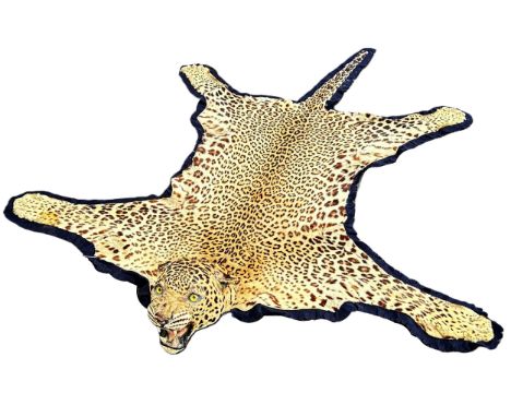Taxidermy interest: An antique leopard skin rug, with mounted and worked head with inset glass eyes, mounted on blue felt bac