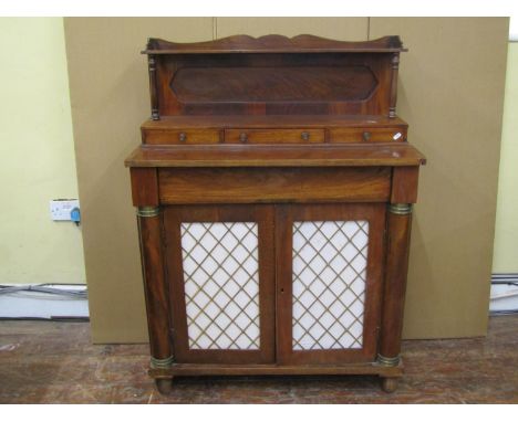 A Regency mahogany chiffonier enclosed by a pair of open doors with brass grille detail, flanked by column supports, raised b
