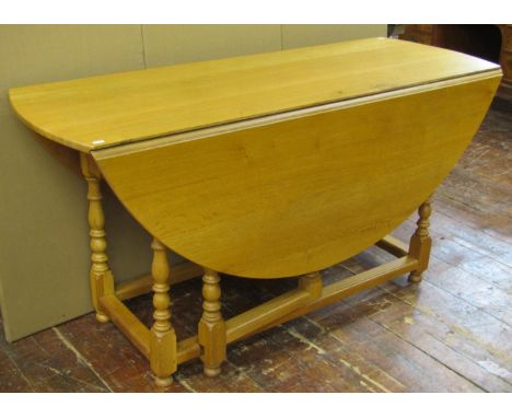 A large light oak old English style oval drop leaf dining table with gateleg action, raised on eight turned supports, 76cm hi