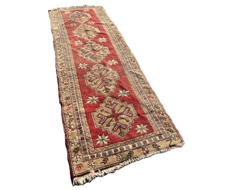 A Turkey runner with five interlocking medallions on a red ground 285cm x 90cm approximately 