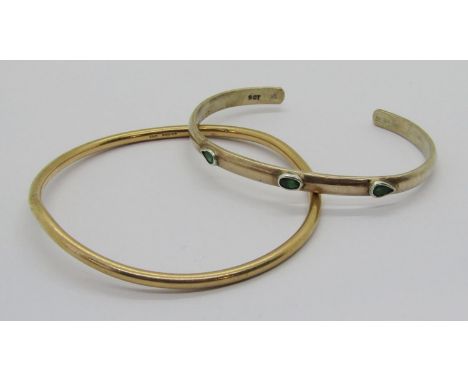 9ct bangle, London 1970, 15.9g (slightly misshapen) and a further 9ct torque bangle set with green gems, signed 'Nomad 2001',