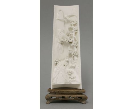 A fine ivory Wrist Rest,c.1900, the tapering half section of tusk minutely carved with two figures in a rocky mountainous lan