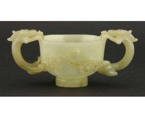 A jade Cup, 19th century, the flared bowl on high foot and encircled by two chilong forming handles, the stone of even pale c