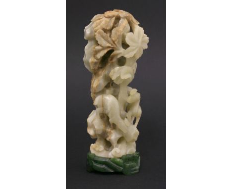 A tall jade Group, 20th century, of two deer on and under towering rocks above waves, the stone pale grey with russet inclusi