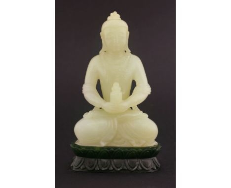 A jade Buddha,20th century, the almost white stone carved with the cross-legged figure holding a jar and cover, his chest wit