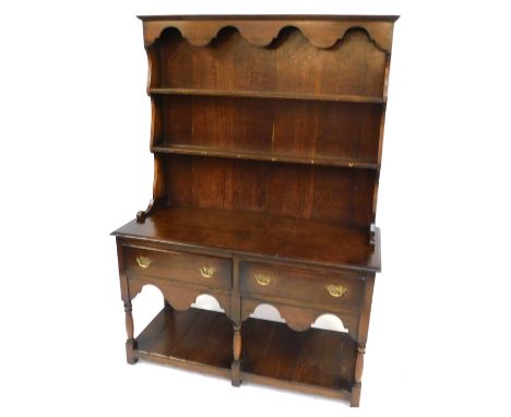 A 20thC oak dresser, with a moulded top above a two shelf plate rack,  above two frieze drawers and shaped apron, raised on t