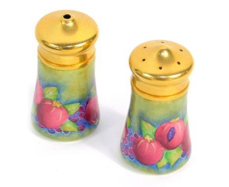 A Moorcroft Pottery miniature enamel salt and pepper decorated in the Pomegranate pattern, 4.5cm high, both boxed.