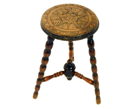 A late Victorian oak tripod stool, with a carved floral top, on bobbin turned legs, 46cm high, 30cm diameter.