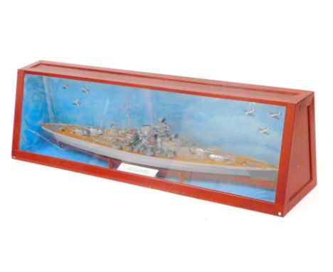 A wooden scale model of the German battleship Bismarck, mounted on a cradle, in a Perspex fronted wooden case, with painted b