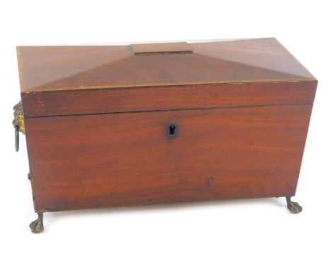 A late Regency mahogany sarcophagus form tea caddy, with brass lion's head and ring handles, the hinged lid opening to reveal