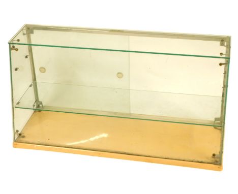 A 20thC table top glass shop display cabinet, with a sloped front and single shelf, on a pink plastic base, 46cm high, 90cm w