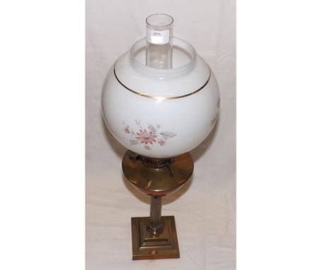 A late 19th/early 20th Century Oil Lamp with clear glass chimney, opaque glass floral decorated shade, brass font raised on a
