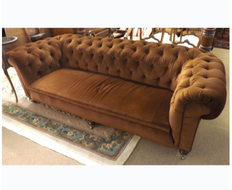 A Victorian Brown Upholstered Button Back Chesterfield Sofa, of typical form, raised on heavy turned legs with brass castors,