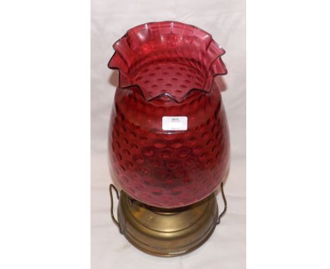 A large late 19th/early 20th Century Oil Lamp or Pulpit Warmer, fitted with a frilled cranberry glass shade to a squat brass 
